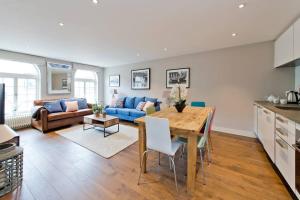 cocina y sala de estar con mesa y sofá azul en *Newly Renovated 2-Bed in Heart of Notting Hill*, en Londres