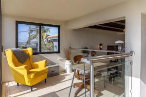 a dining room with a yellow chair and a glass table at Near Downtown w Views of Marina Puerto Los Cabos in La Choya