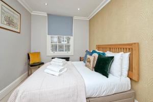 een slaapkamer met een groot wit bed met kleurrijke kussens bij Special offer! Fantastic 1 bed flat in Pimlico in Londen