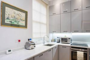 ロンドンにあるSpecial offer! Fantastic 1 bed flat in Pimlicoの白いキッチン(白いキャビネット、電化製品付)