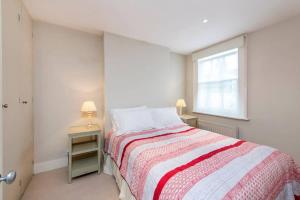 um quarto branco com uma cama e uma janela em Delightful 2 Bed House in Stylish Fulham em Londres