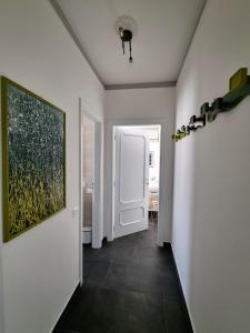 a hallway with white walls and a painting on the wall at Sunbath House Pisa - Free Parking - Near Pisa Center in Pisa