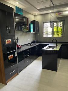 uma cozinha com armários pretos e um balcão preto em THE GREEN CONDO em Elmina