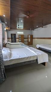 a large bedroom with two beds and a wooden ceiling at Janardhana Residency in Dharmastala