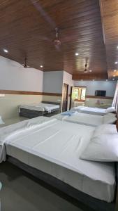 two large beds in a large room with wooden ceilings at Janardhana Residency in Dharmastala