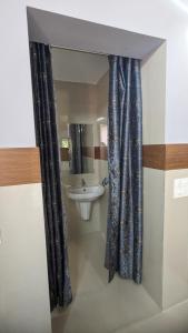 a bathroom with a sink and a shower curtain at Janardhana Residency in Dharmastala