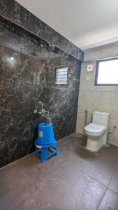 a bathroom with a toilet and a blue stool at Janardhana Residency in Dharmastala