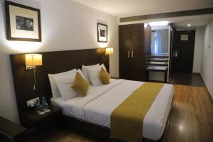 Cette chambre comprend un grand lit avec deux oreillers jaunes. dans l'établissement Hotel Clarks Collection Vadodara, à Vadodara