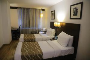 a hotel room with two beds and a desk at Hotel Clarks Collection Vadodara in Vadodara