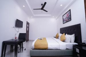 a bedroom with a bed and a table and a ceiling fan at Hotel Moon Taj Near Yashobhoomi Convention Centre in New Delhi