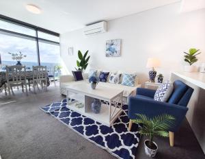 ein Wohnzimmer mit einem Sofa und einem Tisch in der Unterkunft Hamptons Style 2BR & kid room w view in Olympic Park in Sydney