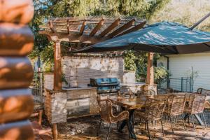 an outdoor grill with a table and chairs and an umbrella at Heritage Log Cabin and Garden w Outdoor Hot Tub in Medlow Bath