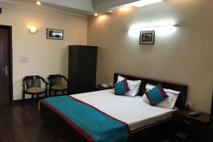 a bedroom with a bed and a chair at OYO Vatika in Gurgaon