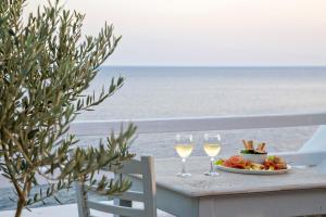 einen Tisch mit zwei Gläsern Wein und einem Obstteller in der Unterkunft Artemis Apartments in Tinos