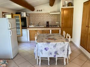 a kitchen with a table and a white refrigerator at Maison au Colorado Provençal in Rustrel
