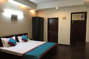 a bedroom with a bed with white sheets and colorful pillows at OYO Vatika in Gurgaon