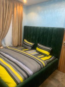 Una cama verde con almohadas amarillas y negras. en BLUE AO HOTEL en Lagos