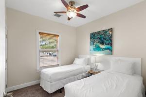 a white bedroom with two beds and a ceiling fan at Mesa House, Dos by Brightwild-Unreal Location in Key West