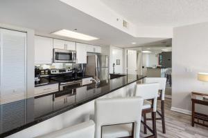 a kitchen with white cabinets and a counter with white chairs at The Andros by Brightwild-4th Floor Sunset View in Key West