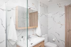 a bathroom with a sink and a glass shower at Etheria Comfort House in Kos