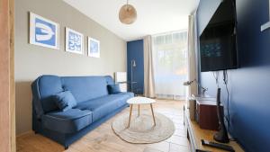a living room with a blue couch and a tv at Apartamenty Sun & Snow Villa Verona in Mielno