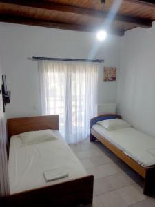two twin beds in a room with a window at Venus cottage in Agios Vlasios
