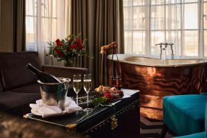 a bathroom with a tub and a bottle of champagne and glasses at Hotel Gotham in Manchester