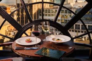 a table with two plates of food and wine glasses at Hotel Gotham in Manchester
