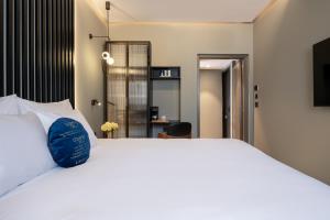 a bedroom with a large white bed with a blue pillow at Hotel Poli Urban in Tel Aviv