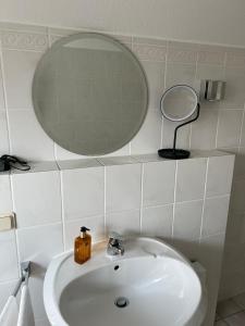 een witte badkamer met een wastafel en een spiegel bij Messewohnung für 2 in Giesen