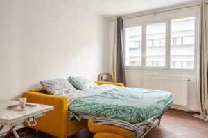Un dormitorio con una cama amarilla y una mesa en Superbe Studio Paris Gambetta, en París