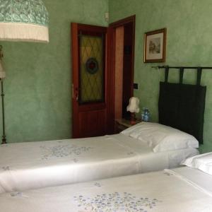 2 letti in una stanza con pareti verdi e porta di Beb Villa Aurora a Carmagnola