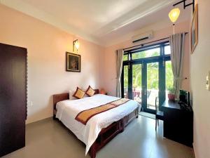 a bedroom with a bed and a large window at Ngan Phu Villa in Hoi An