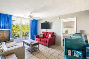 a living room with a couch and a red chair at The Barbados by Brightwild-Bright Condo w Pool in Key West