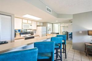 a large kitchen with blue chairs and a counter at The Barbados by Brightwild-Bright Condo w Pool in Key West