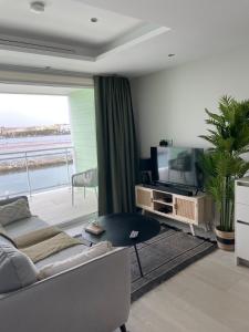 een woonkamer met een bank en een televisie bij Marina Club Luxury private studio with Pool and incredible views in Gibraltar