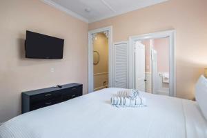 a bedroom with a white bed with a tv on the wall at Creme Brulee Suite by Brightwild in Key West