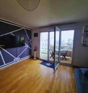 uma sala de estar com portas de vidro deslizantes e uma televisão em L'agréable Nid de Verdun. em Limeil-Brévannes