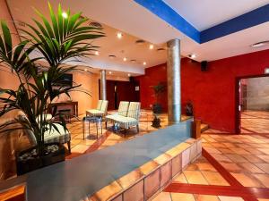 eine Lobby mit Stühlen und Pflanzen in einem Gebäude in der Unterkunft Hotel Vila de Tossa in Tossa de Mar
