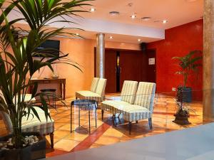 - un hall avec des chaises, une table et une plante dans l'établissement Hotel Vila de Tossa, à Tossa de Mar