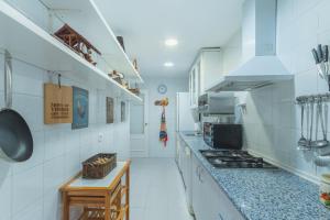 una cocina con paredes de baldosas blancas y encimera. en Amplio y luminoso apartamento de 2 dormitorios cerca de la plaza del Caballo, Jerez de la Frontera, en Jerez de la Frontera
