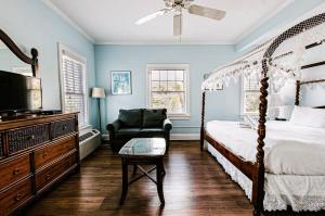 1 dormitorio con cama con dosel y silla en Deluxe King with Balcony by Brightwild- at James House with Parking!, en Key West