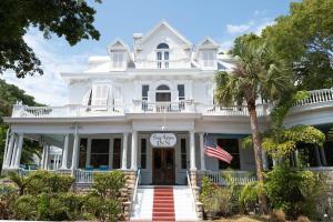 a white house with a palm tree in front of it at Deluxe King with Balcony by Brightwild- at James House with Parking! in Key West