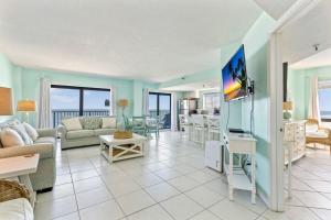 a living room with a couch and a tv at Ocean Front Penthouse with Incredible Views! Sunglow Resort 1003 by Brightwild in Daytona Beach Shores
