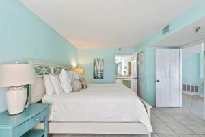 a bedroom with a white bed and a blue wall at Ocean Front Penthouse with Incredible Views! Sunglow Resort 1003 by Brightwild in Daytona Beach Shores +34 photos