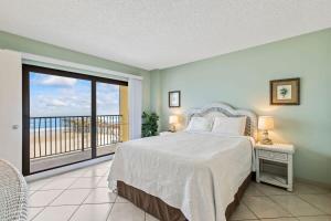 a bedroom with a bed and a balcony at Ocean Front Condo with Amazing Views! Sunglow Resort 402 by Brightwild in Daytona Beach Shores