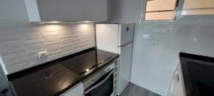 a white kitchen with a refrigerator and a window at Siesta Mar Apartamentos Ibiza in Santa Eularia des Riu