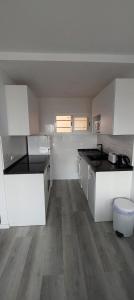 cocina con armarios blancos y suelo de madera en Siesta Mar Apartamentos Ibiza en Santa Eulalia del Río