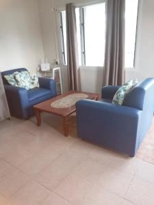 ein Wohnzimmer mit 2 blauen Stühlen und einem Tisch in der Unterkunft Lelago Eco Lodge in Apia