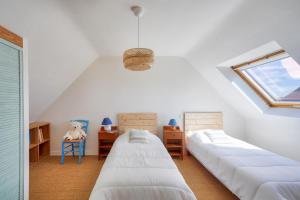 a attic bedroom with two beds and a window at Vue mer ! À 200m de la plage, maison pour 9 in Plovan